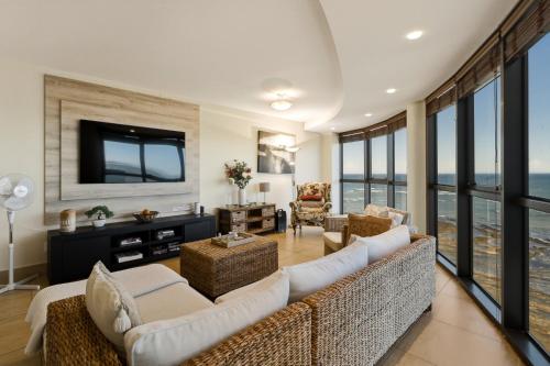 a living room with a couch and a tv at Luxury Ocean View 1203 with Workspace, AC & Beachfront Location in Cape Town