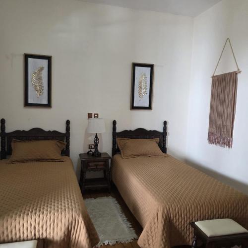 a bedroom with two beds and a table with a lamp at Hotel Posada San Rafael in Pátzcuaro