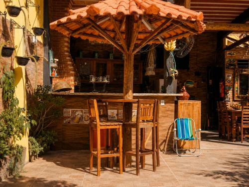 an outdoor bar with chairs and an umbrella at Pousada Mirante Pôr do Sol in Maricá