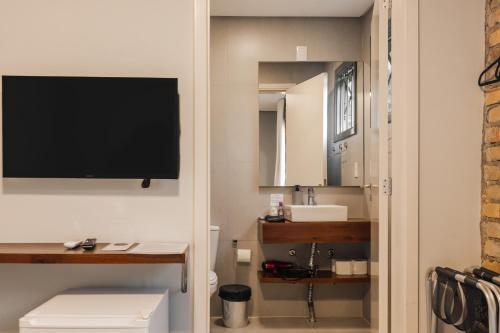 a bathroom with a toilet and a television on a wall at Pousada Calza - Vale dos Vinhedos - Bento Gonçalves in Bento Gonçalves