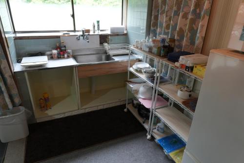 a kitchen with a sink and a counter with shelves at COSMOS Iya Valley in Akano