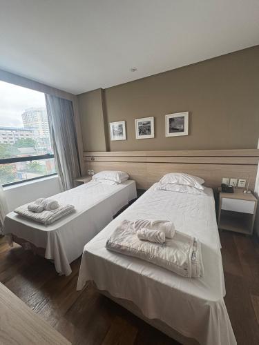 a hotel room with two beds and a window at Intercity - Apartmento 412 in Manaus