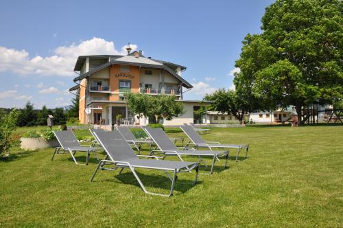 a row of lounge chairs in the grass in front of a building at Karglhof Stammhaus in Faak am See