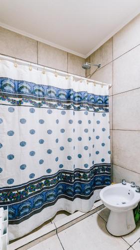 a bathroom with a shower curtain and a toilet at Casa Las Dunas in Monte Hermoso