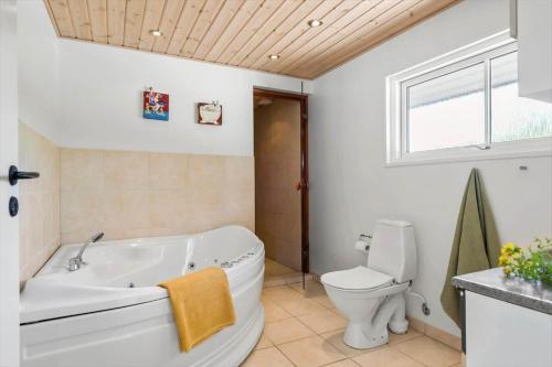 a bathroom with a tub and a toilet and a window at 8585-Glesborg-Tangvej-33 in Glesborg
