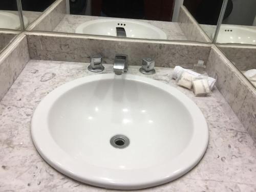 a white bathroom sink with towels on a counter at Hotel Rivera in Oaxaca City