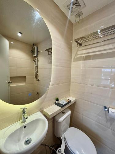 ein Badezimmer mit Waschbecken, Toilette und Spiegel in der Unterkunft Pacific Park Hotel in Manila