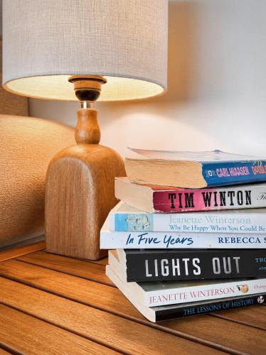 a stack of books on a table next to a lamp at Oceanfront Escape with Private Bath and Beach Access in Gibsons