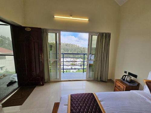 a bedroom with a bed and a view of a balcony at SAAI Rosorts iin Yercaud in Yercaud