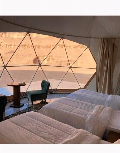 a tent with two beds and a table and a chair at Wadi Rum Elara Luxury Camp in Wadi Rum