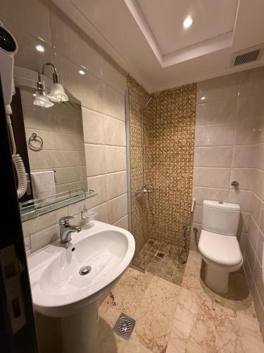 a bathroom with a sink and a toilet at فندق ميراب الروضة in Al Khansāk