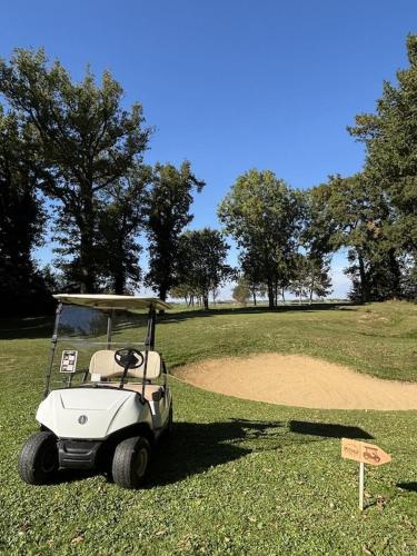 a golf cart parked on a golf course at Les sarrays Golf et Lodges in Neuvy-Pailloux