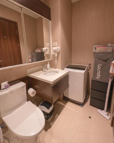 a bathroom with a toilet and a sink and a mirror at Deluxe Studio-Condo at Tambuli Seaside Living in Maribago