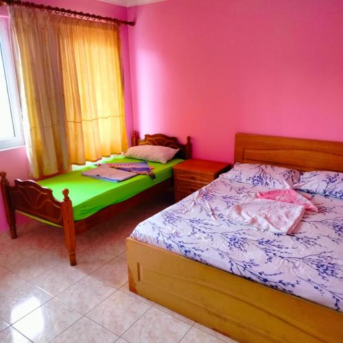 two beds in a room with pink walls at Beach Guest House in Durrës