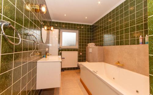 a bathroom with a tub and green tiled walls at Wattknistern in Garding