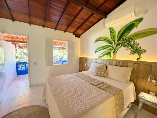 a bedroom with a bed and a plant on the wall at Pousada Nascente do Sol in Ilha de Boipeba
