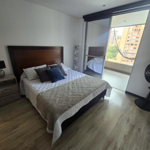 a bedroom with a large bed and a large window at Apartamento terraza hamaca - doble parqueadero - Provenza in Medellín