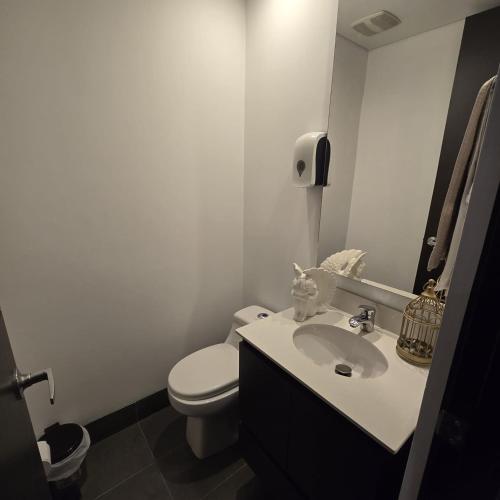 a white bathroom with a toilet and a sink at Apartamento terraza hamaca - doble parqueadero - Provenza in Medellín