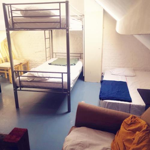 a room with two bunk beds and a couch at Trapmouse hostel in Brussels