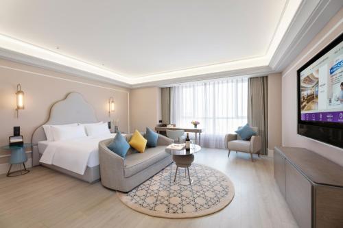a hotel room with a bed and a television at Mercure Urumqi Doowin Wanda Plaza in Ürümqi
