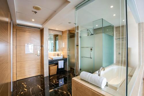 a bathroom with a glass shower and a tub at 泰安宝龙艺珺酒店 in Tai'an