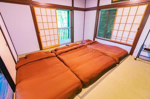 an orange bed in a room with windows at Luminous Komoro in Komoro