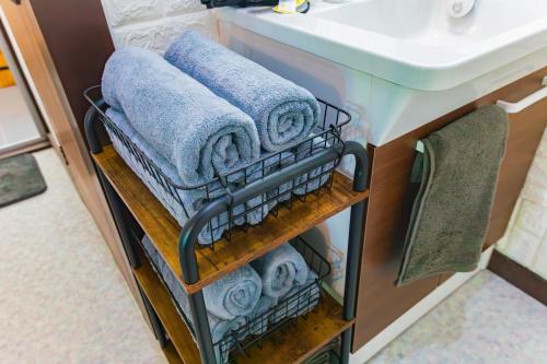 a towel rack under a bathroom sink with towels at Luminous Komoro in Komoro