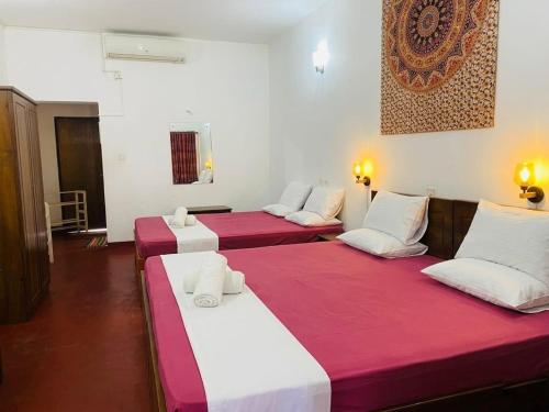 three beds in a room with red and white sheets at Happy Beach hotel nilaveli in Nilaveli