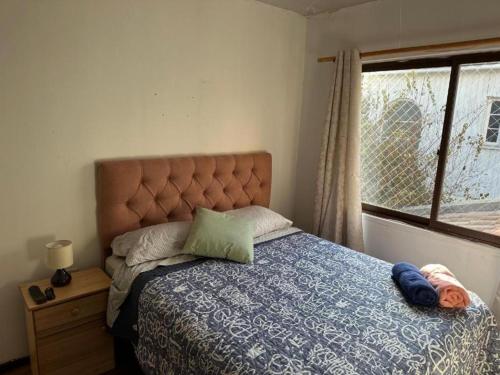 a bedroom with a bed with a blue comforter and a window at HOSTEL Gloria Economy in Viña del Mar