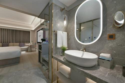 a bathroom with a sink and a large mirror at Mercure Urumqi Doowin Wanda Plaza in Ürümqi