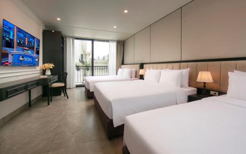 a hotel room with three beds and a tv at Euphoria Hotel & Spa in Hanoi