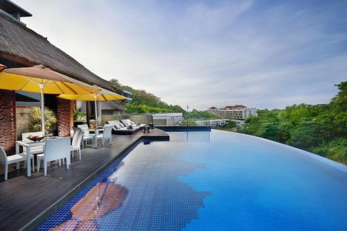 a swimming pool with chairs and umbrellas next to a building at The Sterling Villas in Uluwatu