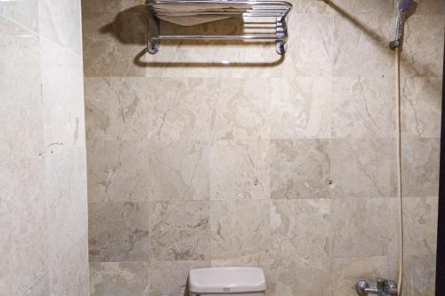 a bathroom with a toilet and a tiled wall at SNUZ Hotel Menteng in Jakarta