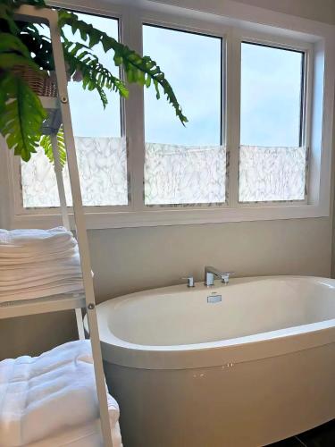 a bath tub in a bathroom with two windows at NEW Spacious BR with Ensuite Bathroom in Innisfil