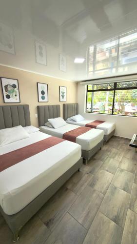 a room with three beds in a room at Hotel Nakama in Medellín