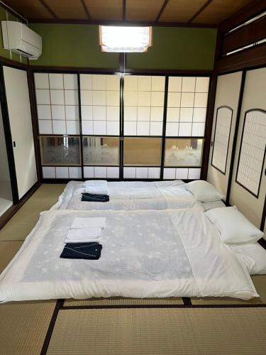 a large white bed in a room with windows at 悠の宿 in Katsuyama