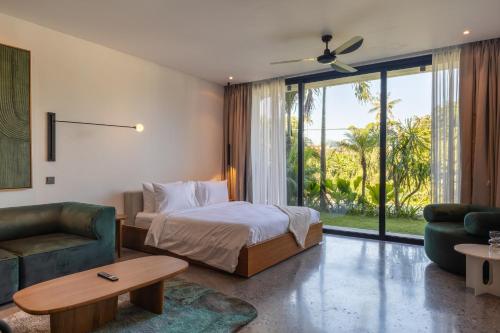 a bedroom with a bed and a couch and a table at Ecoverse Resort & Residence by OXO - Nyanyi Beach, Bali in Cemagi