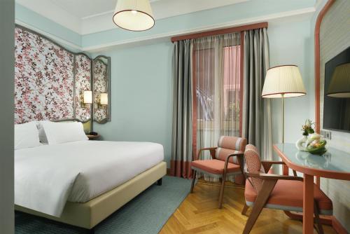 a hotel room with a bed and a desk at Grand Hotel Savoia Genova, Curio Collection by Hilton in Genoa