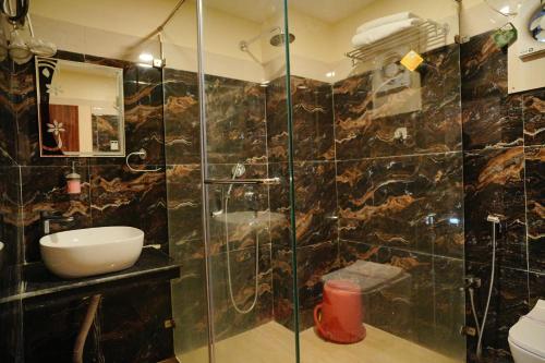 a bathroom with a shower with a sink and a toilet at Hotel Aarohi in Tarapith