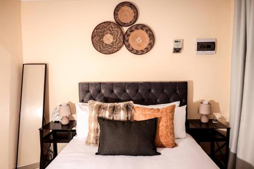 a bedroom with a bed with pillows and plates on the wall at Elite Garden Cabin, Cozy Hideaway in Welkom with Fast WiFi, Free Parking in Welkom