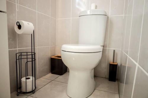 a white toilet in a bathroom with a roll of toilet paper at Elite Garden Cabin, Cozy Hideaway in Welkom with Fast WiFi, Free Parking in Welkom