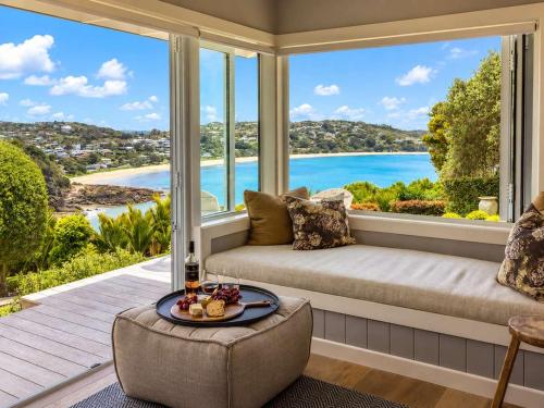 a living room with a couch and a large window at Smiths Cottage - Stay Waiheke in Oneroa