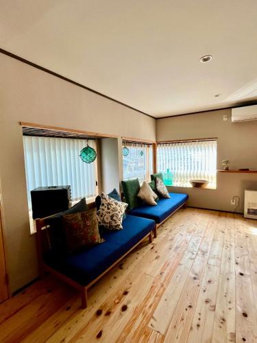 a living room with a blue couch and two windows at NouHarborVilla in Itoigawa