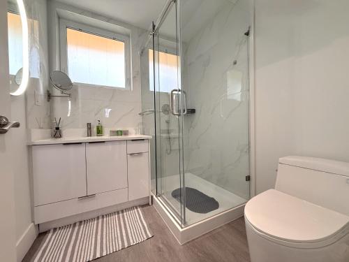 a white bathroom with a shower and a toilet at Vancouver Mandy Laneway Home in Vancouver