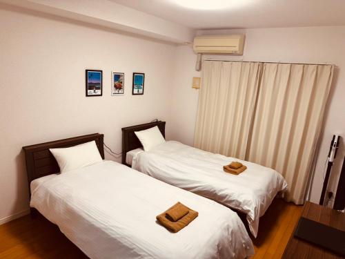 two beds sitting next to each other in a room at オンブラージュ九品寺203-無料駐車場付き-繁華街まで徒歩圏内-南向きで明るいワンルーム in Kumamoto