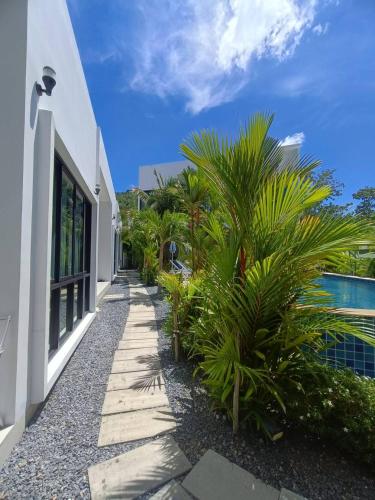 a pathway next to a building with palm trees at Lamai Sunshine Villas in Hua Thanon Beach