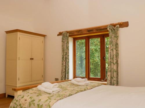 a bedroom with a bed with two towels on it at The Hay Barn in Halwell