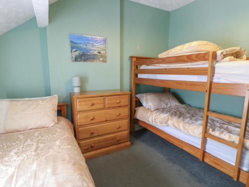 a bedroom with two bunk beds and a dresser at Halford Hill in Llanberis