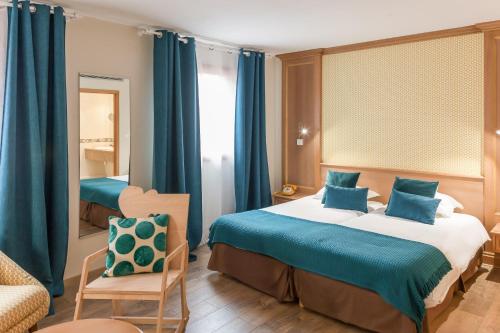 um quarto com uma cama, uma cadeira e um espelho em Hôtel Le Rapp em Colmar