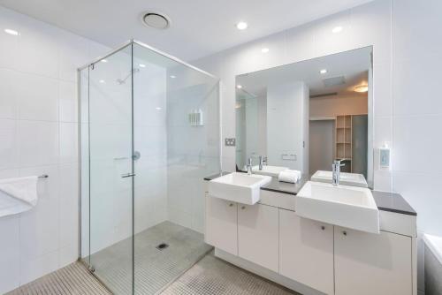 a bathroom with two sinks and a glass shower at C Bargara Unit 101 in Bargara